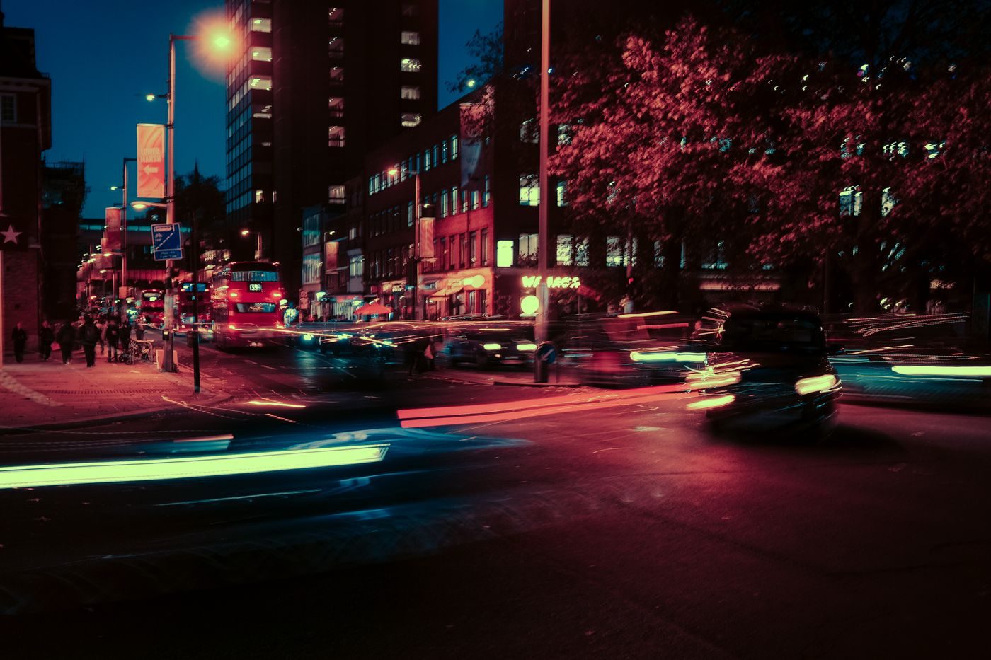 Busy London street at night with light trails from traffic