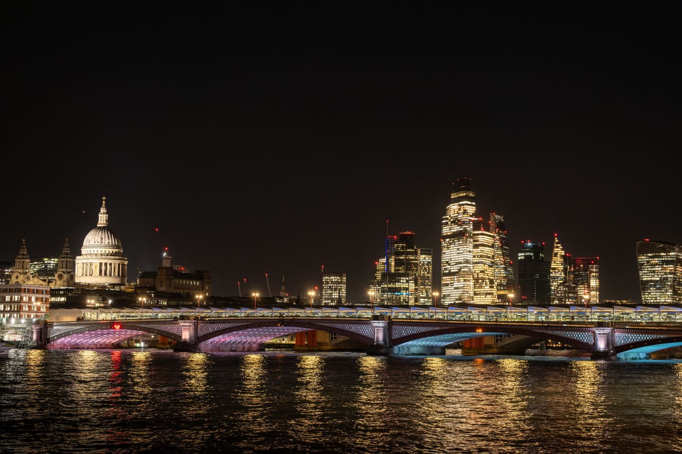 St Paul's Cathedral and the London skyline lit up at night across the river