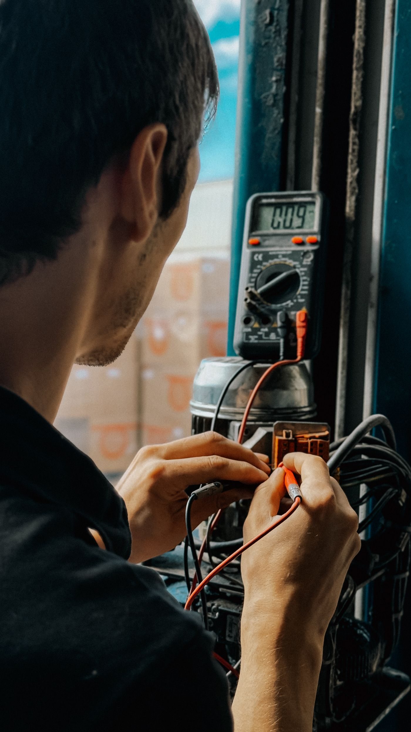 Electrician testing circuits with a multimeter and test leads